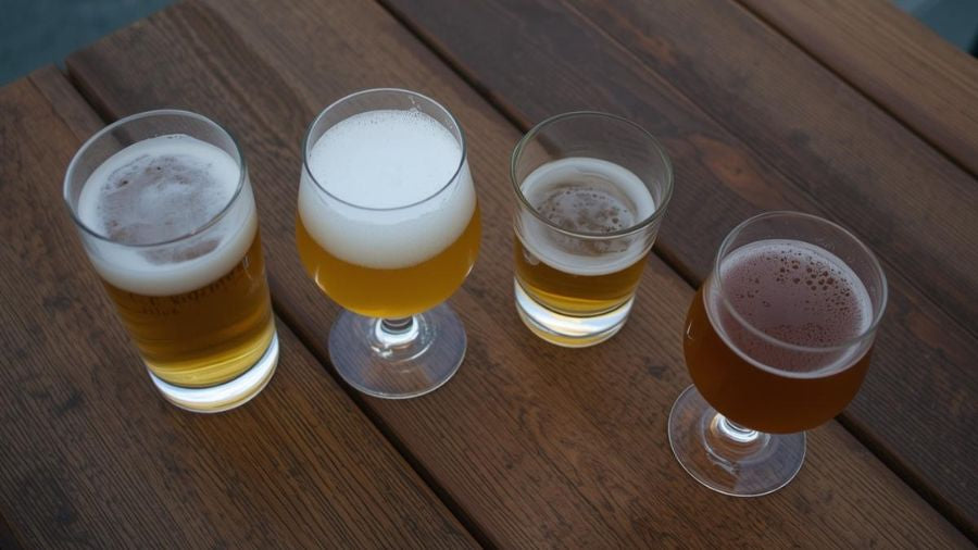 Quatre verres de bières artisanales de styles différents sur une table en bois pour l'apéritif.